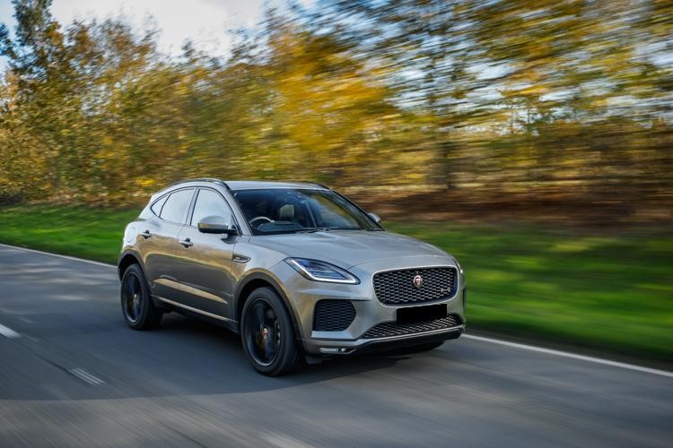 Silver Jaguar I-Pace driving on tar surrounded by forest