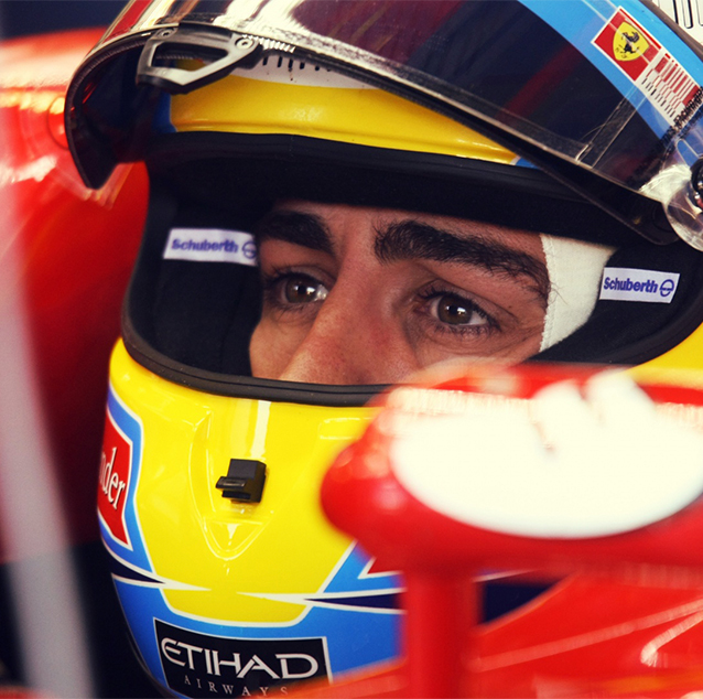 Fernando Alonso sitting in car cockpit, wearing a yellow and blue Etihad labelled helmet.