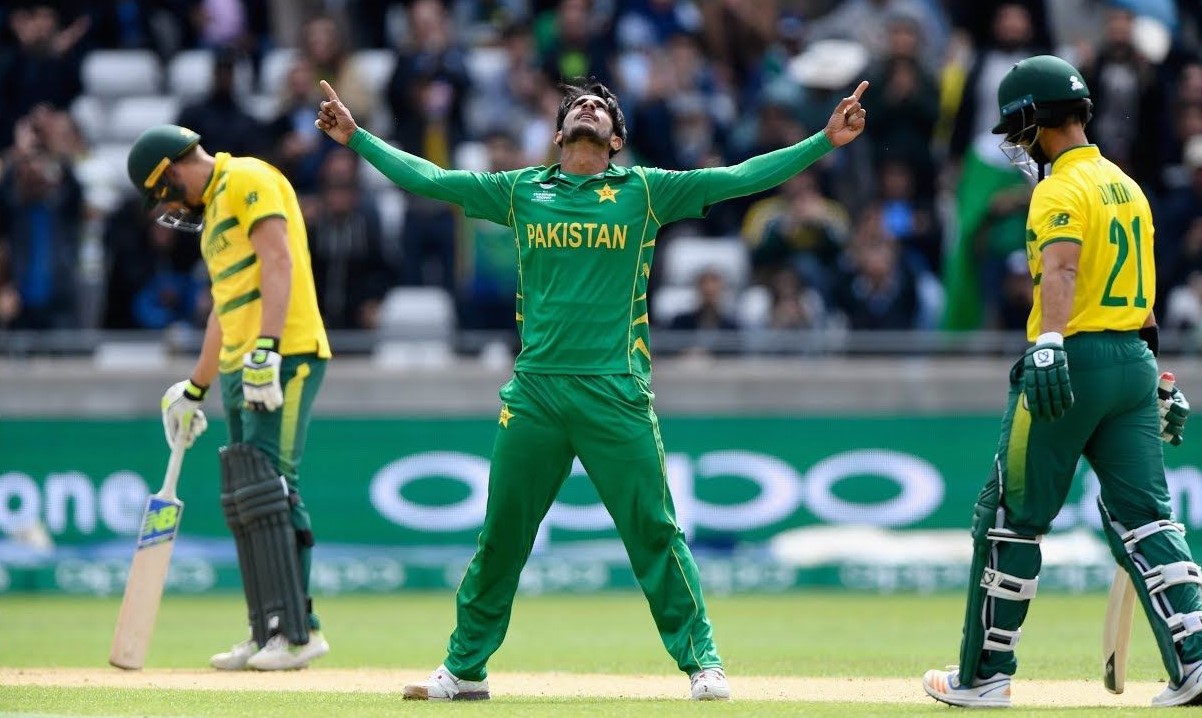 Pakistan cricket player celebrating a victory standing in between two Australian batsmen.