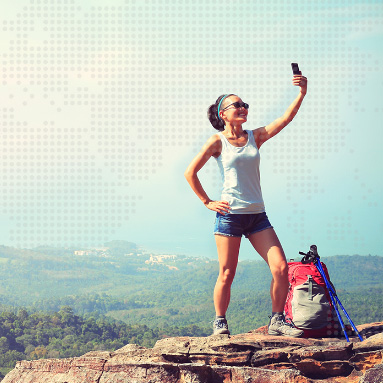Lady standing at top of a mountain taking a selfie with the beautiful landscape in the background | Product offers | Hippo.co.za partner