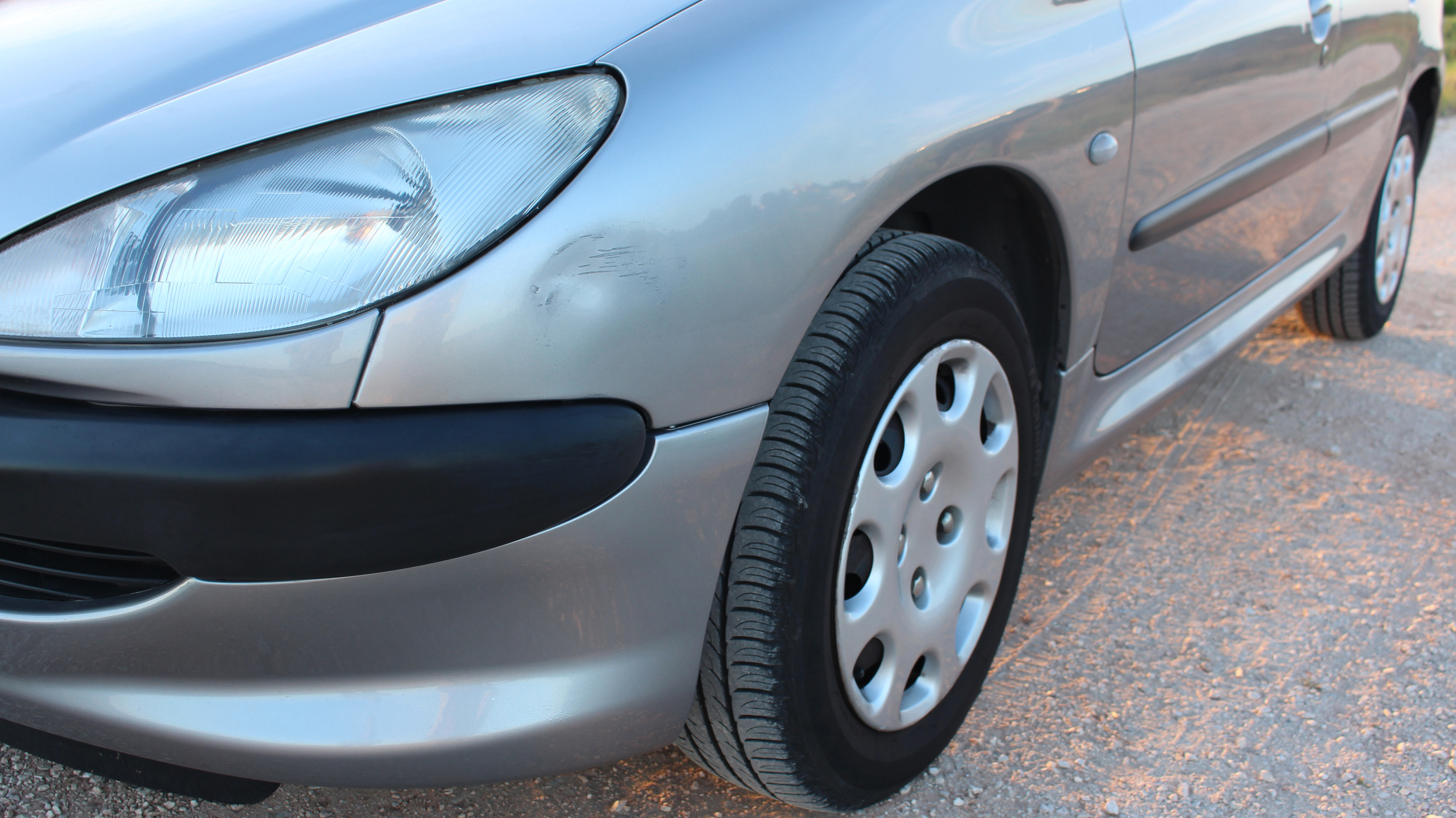 Secondhand car detail showing silver paint, headlight assembly and wheel condition