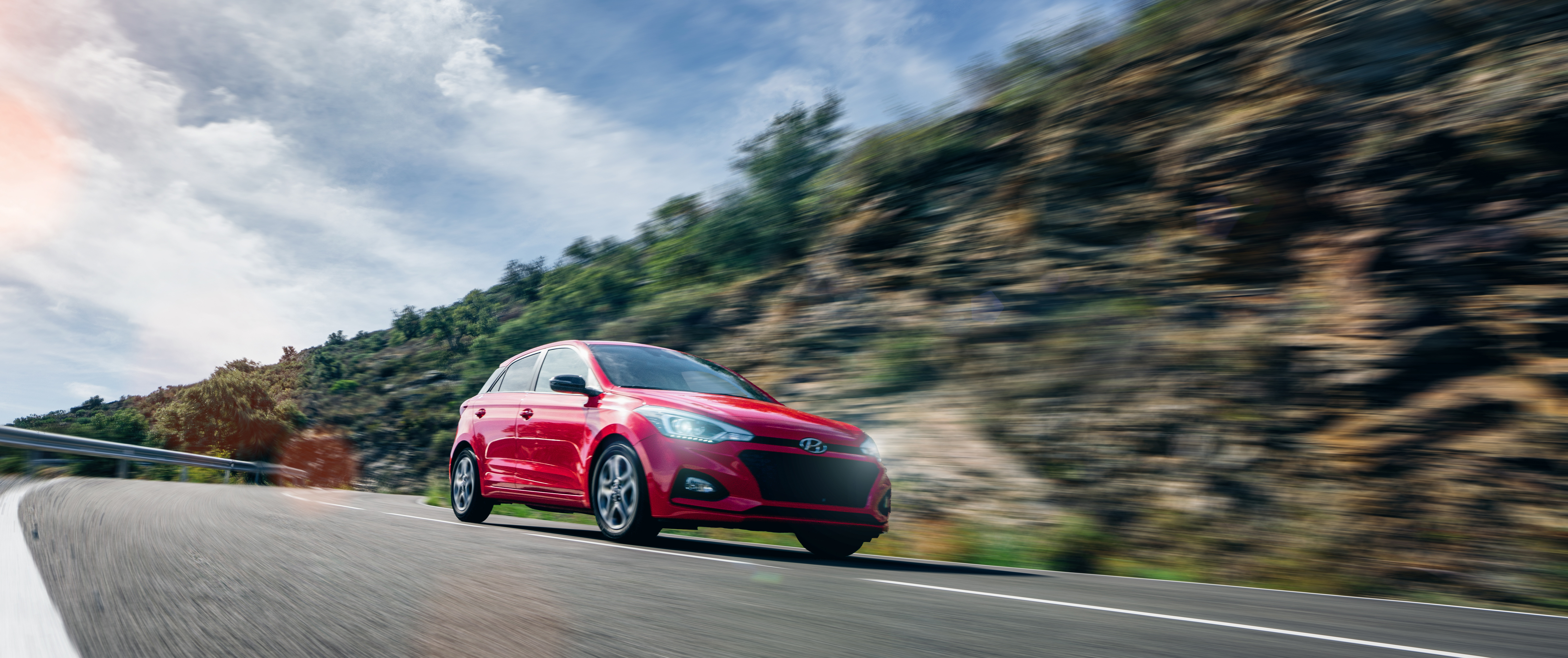 Red Hyundai i20 driving on a mountain road