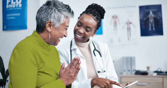 Smiling doctor showing tablet to elderly patient, demonstrating personalized medical aid services