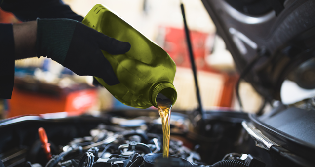 Mechanic pouring fresh oil during motor warranty service maintenance check 