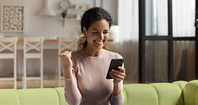 Woman on green couch smiling at smartphone, celebrating Medical Aid Rewards Programmes benefits