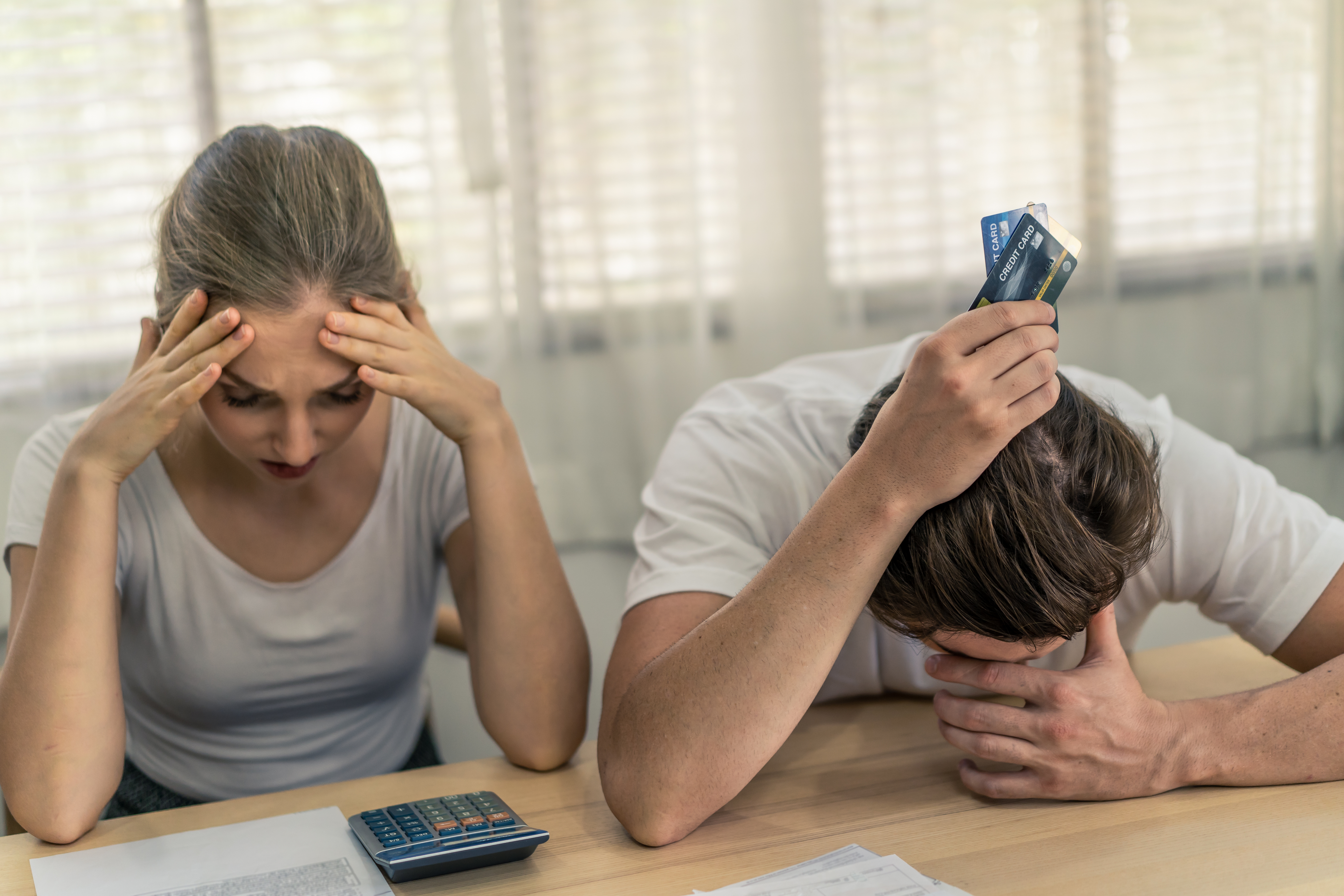 Stressed couple with credit cards and calculator reviewing finances during Januworry  