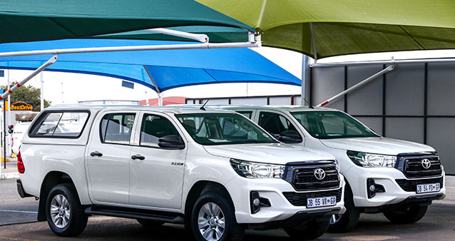 Toyota pickup trucks parked under colourful canopies, popular vehicles for comprehensive car insurance in South Africa