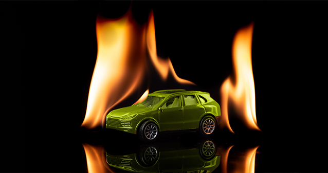 Green toy car surrounded by flames, highlighting the importance of fire coverage in car insurance in South Africa