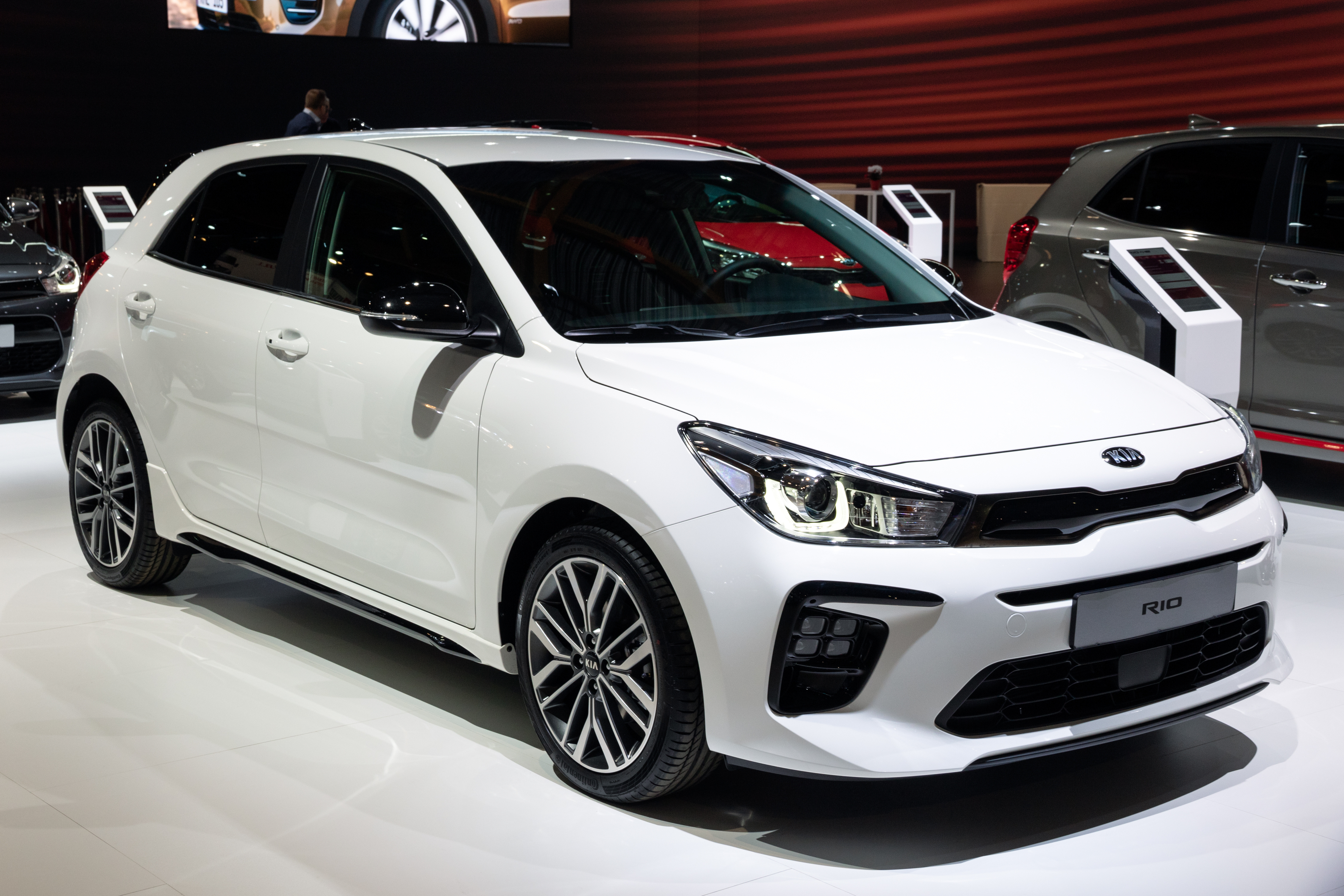 white kia rio on display in a car showroom, highlighting the compact and reliable features ideal for affordable car insurance coverage.