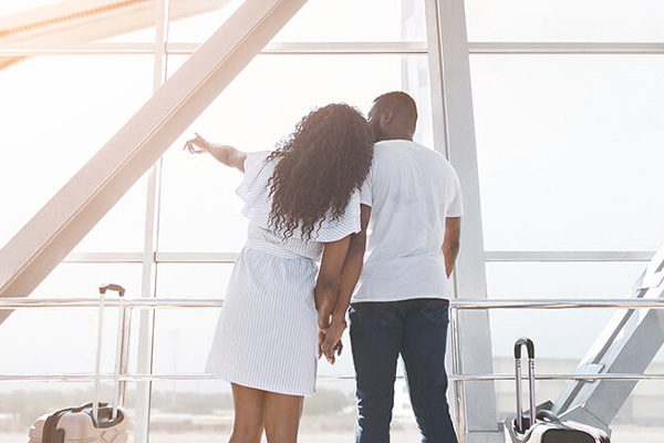 Couple with suitcase looking out airport window