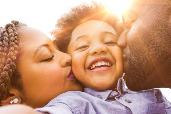 Parents kissing child 